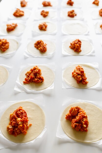 Photo kitchen table full of empanadas ready to be closed and cooked