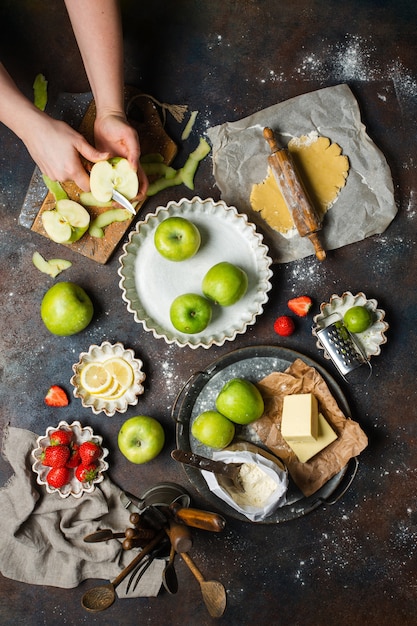 Kitchen table with apples, flour, butter, strawberries, and lemon