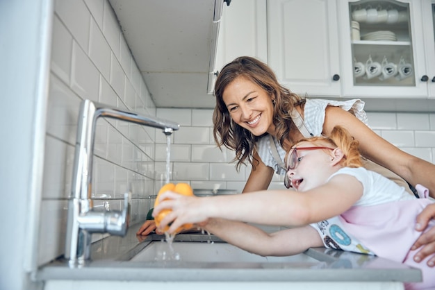 Photo kitchen tap vegetables and mom with child washing yellow pepper growth and development in happy home love smile and mother and toddler girl wash vegetable in running water for healthy salad lunch