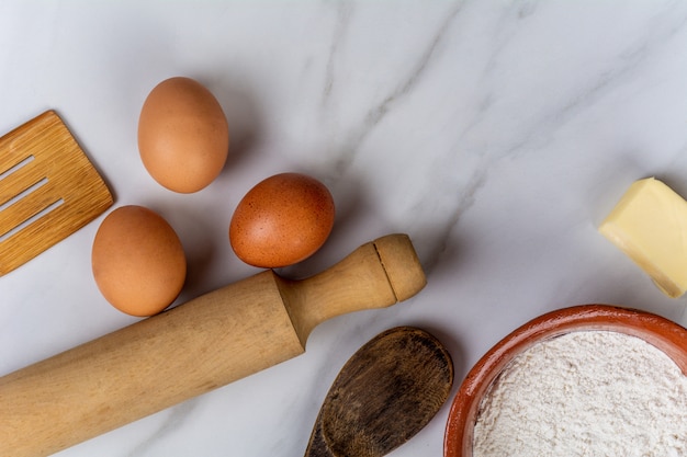 Kitchen tools, eggs, flour and butter.