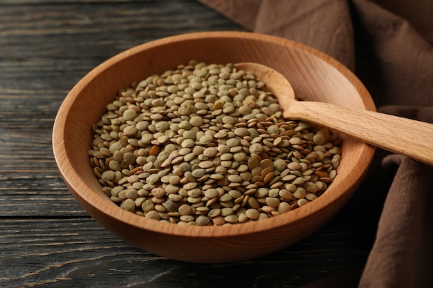 Kitchen towel, bowl with legumes and spoon on wooden table