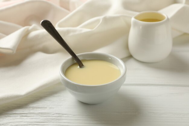 Kitchen towel and bowls with condensed milk on wooden background