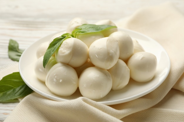 Kitchen towel with plate with mozzarella and basil on wooden background