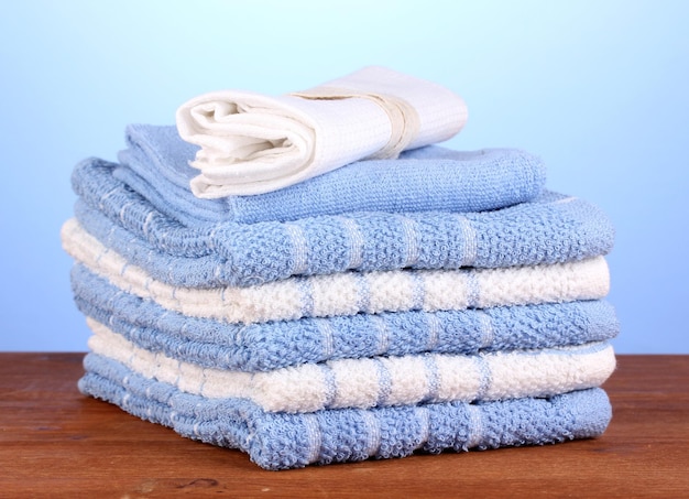 Kitchen towels on wooden table on blue background closeup