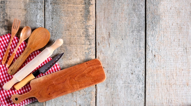 Kitchen utensil tools on rustic wooden background.