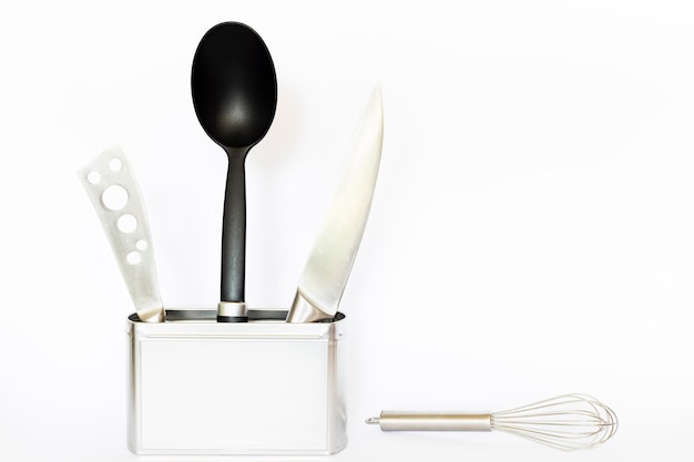 Photo kitchen utensils in container against white background