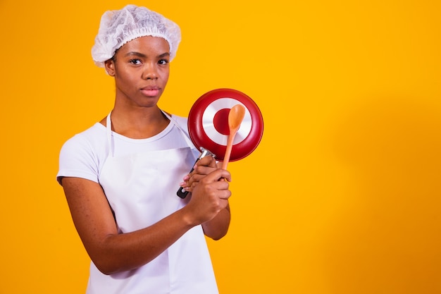 Kitchen utensils. Cooking woman in kitchen with frying pan and wooden spoon. housewife banging pan