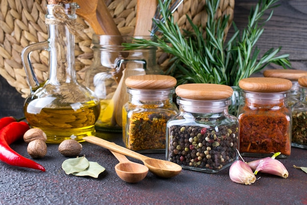 Kitchen utensils, herbs, colorful dry spices in glass jars on dark  surface