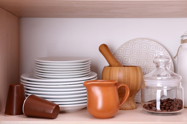 Kitchen utensils and tableware on wooden shelf