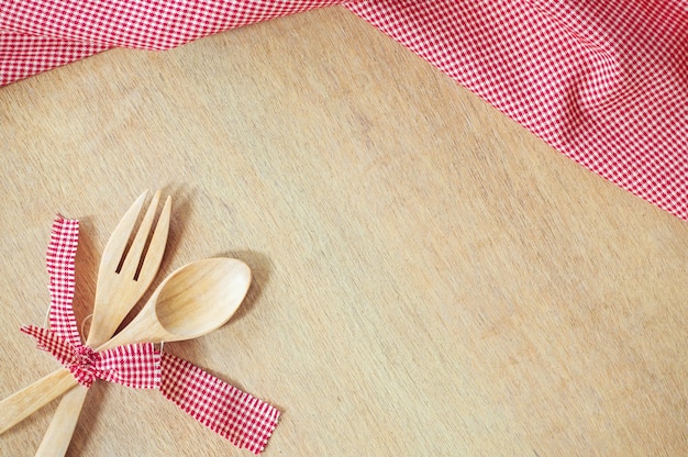 Kitchen utensils. Wooden fork and spoon with red fabric on wooden background