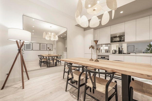 Kitchen with gray cabinets with white stone countertop mirrored wall stoneware floors and wooden deck and wooden plank dining table with matching chairs in front of a large square mirror