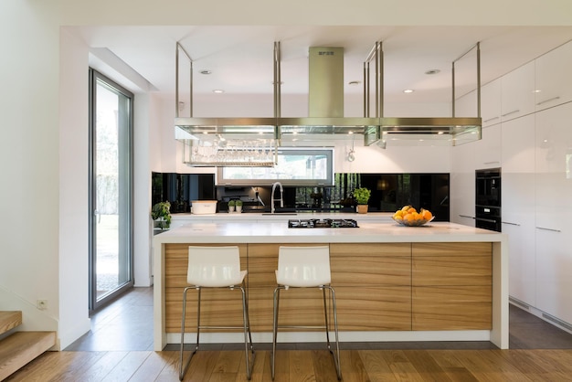 A kitchen with a large island with a white countertop and a white countertop with a glass door that says'the kitchen is open to the outdoors '