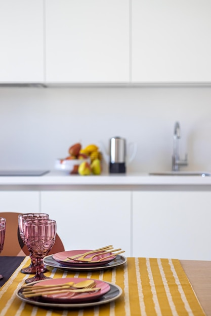 A kitchen with a sink, plates, and glasses on a table.