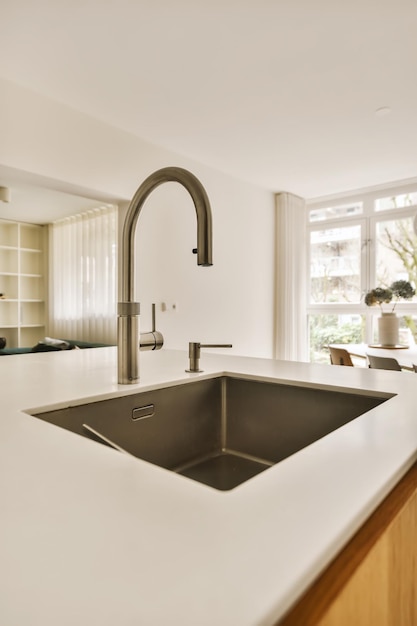 A kitchen with white counter tops and wood cabinets in the background there is an open window to the outside