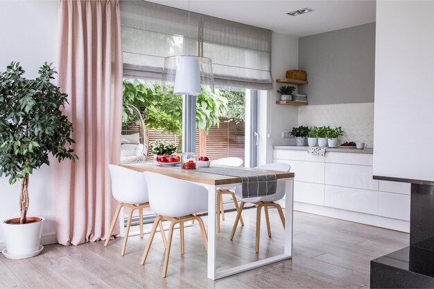 A kitchen with a white table and chairs and a window with curtains