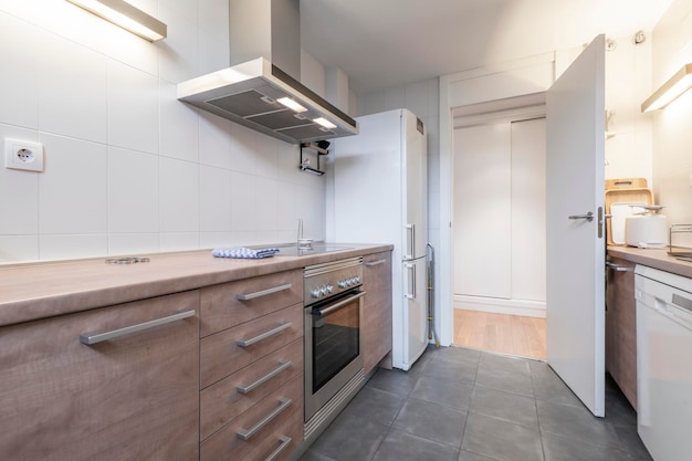 Kitchen with wooden furniture and worktop in the same tone with white and stainless steel appliances with gray terrazzo floors