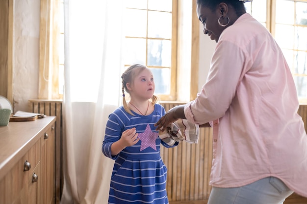 In the kitchen. Woman cleaning hands of a girl with a towel