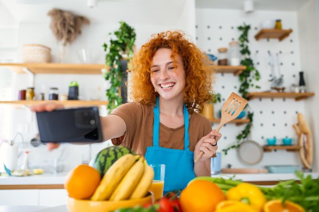 キッチンで女性が料理中にセルフィーを撮る 彼女の笑顔は料理の喜びを補う