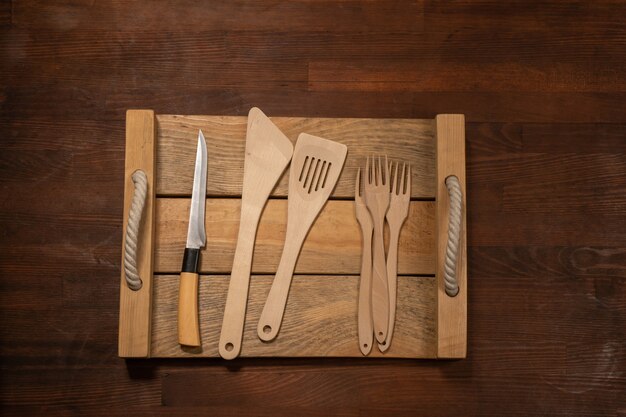 Kitchen wooden utensils on wooden table horizontal banner layout. Top view on wooden table background.