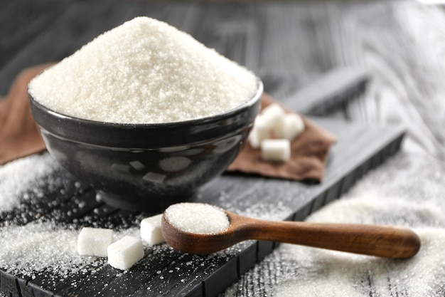 kitchenware with white sand and lump sugar on black wooden background
