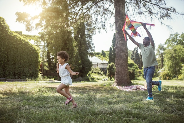 写真 凧。凧の遊び方を子供に見せている浅黒い肌の男