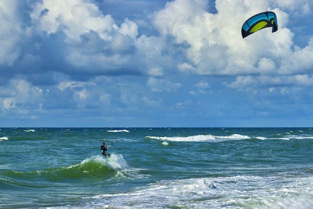 Kitesurfer on the crest of a wave. Blue sky with white clouds and turquoise sea