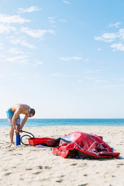 Kitesurfer inflate his kite in the beach.