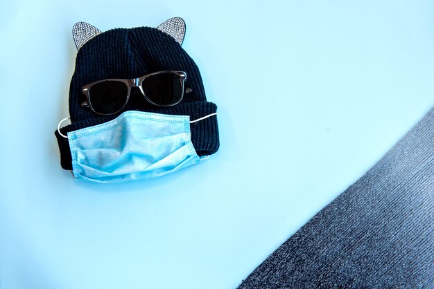 Kitten cap, glasses and scarf on blue background. Top view.