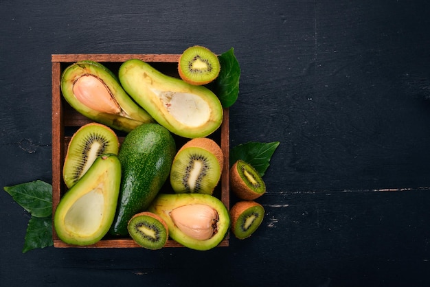 Kiwi e avocado in un cesto di legno su uno sfondo di legno vista dall'alto spazio libero per il testo