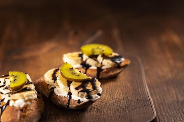 Kiwi and banana sweet sandwiched with chocolate sauce on wooden background. High quality photo