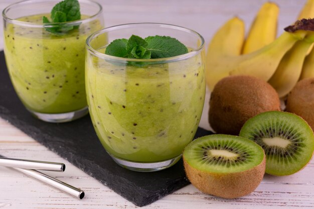 Kiwi- en bananensmoothies in glazen op een zwart bord om te serveren