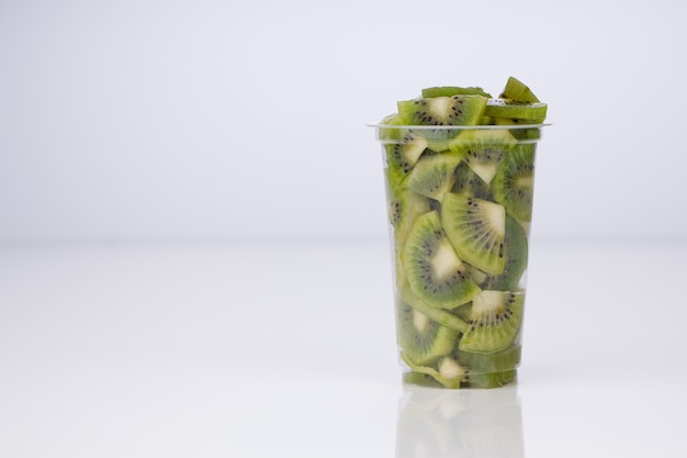 Kiwi fruit slices or cut piece arranged in a transparent glass with white color background.