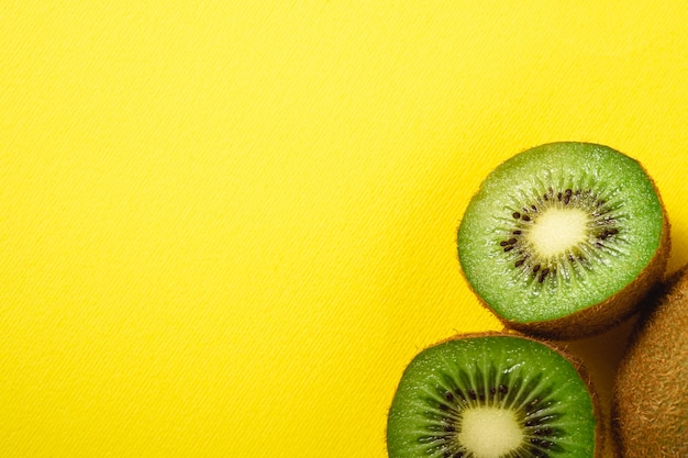 Kiwi fruits half sliced on vibrant plain yellow