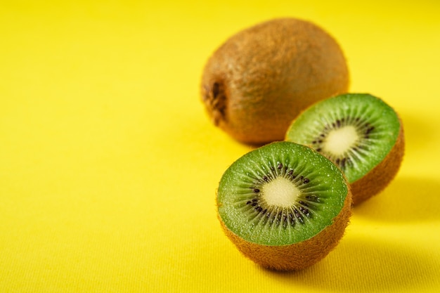 Kiwi fruits half sliced on vibrant plain yellow