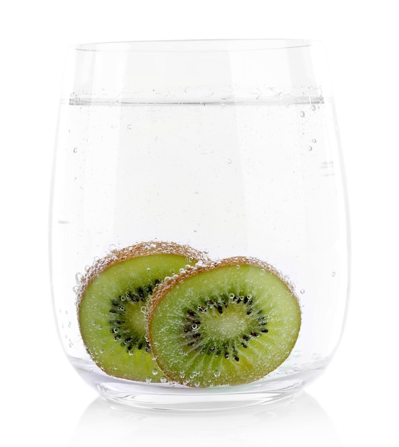 Photo kiwi in glass of water isolated on white
