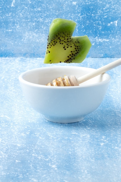 Kiwi heart dropping into white bowl.