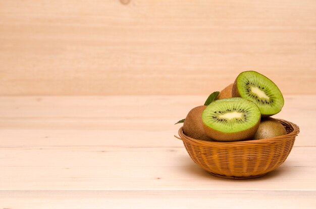 Kiwi in een mand op een houten achtergrondexemplaarruimte