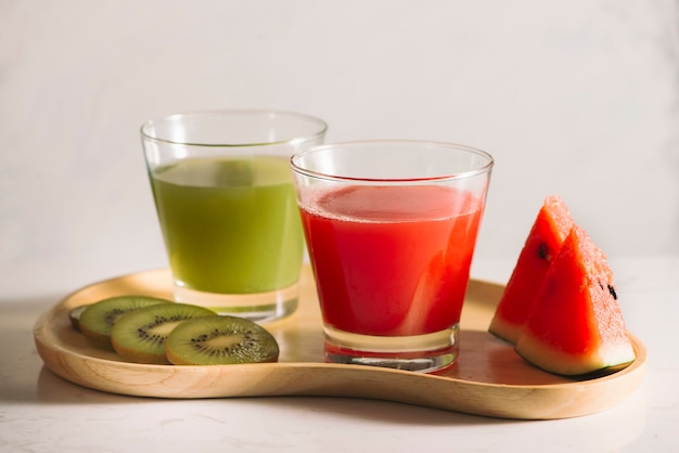 Succo di kiwi e anguria con fette di frutta su vassoio in legno