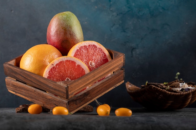 Kiwi, kinkans en grapefruit segmenten in een houten bakje