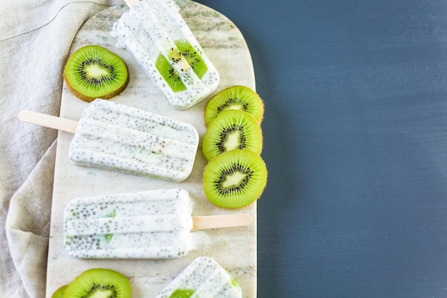 Kiwi kokos chia ijslollys op granieten bord.