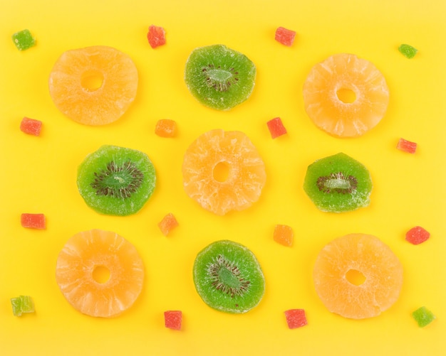 Kiwi and pineapple dried fruits near to candied fruits, sweet colorful background