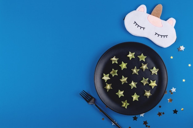 Ломтики киви в форме звезд на тарелке как продукт для восстановления здорового сна на синем.