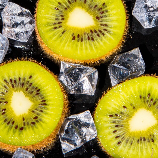 Kiwi slices with ice and water drops on a black background macro photography