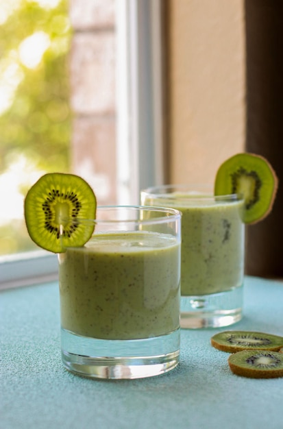 kiwi-smoothie in een glas op blauwe achtergrond, onscherpe achtergrond