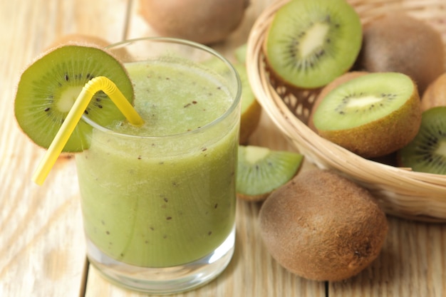 Kiwi-smoothies in een glas naast verse kiwiplakken op een natuurlijke houten tafel.