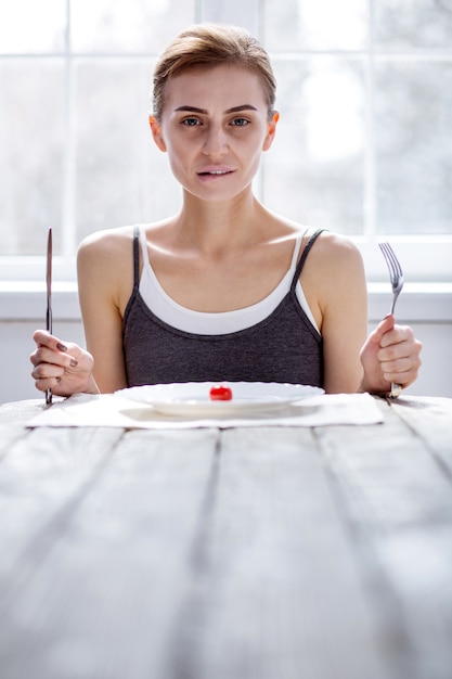 Klaar om te eten. leuke bleke vrouw die een vork en een mes vasthoudt terwijl ze klaar is om te eten