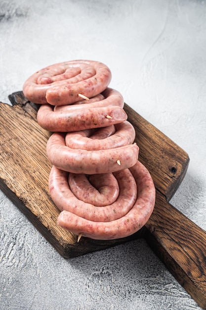 Klaar om te koken Rauwe spiraal varkensvlees worstjes op een houten bord Witte achtergrond Bovenaanzicht