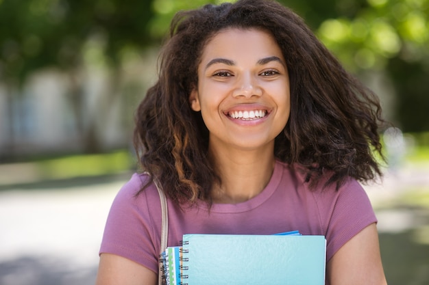 Klaar om te studeren. Een meisje in een roze t-shirt met studieboeken in haar handen