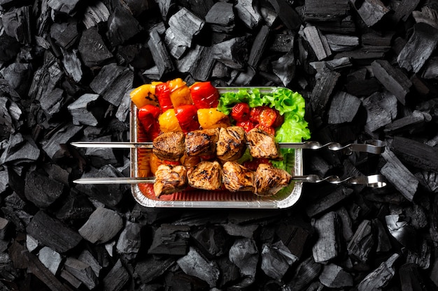 Klaar shish kebab. Gegrilde groenten en vlees op een spies in een aluminium wegwerp container.