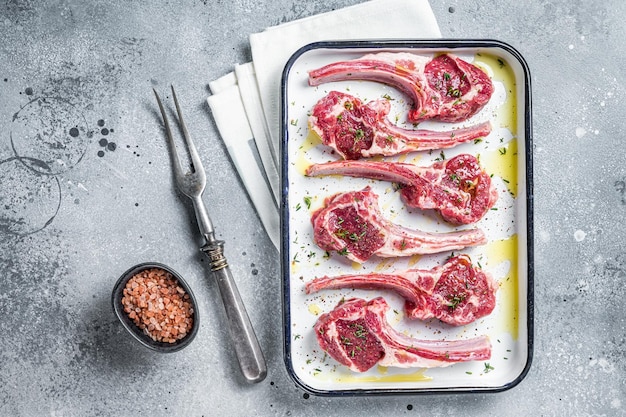 Klaar voor het koken van rauwe lamskoteletsteaks met specerijen en kruiden Grijze achtergrond Bovenaanzicht